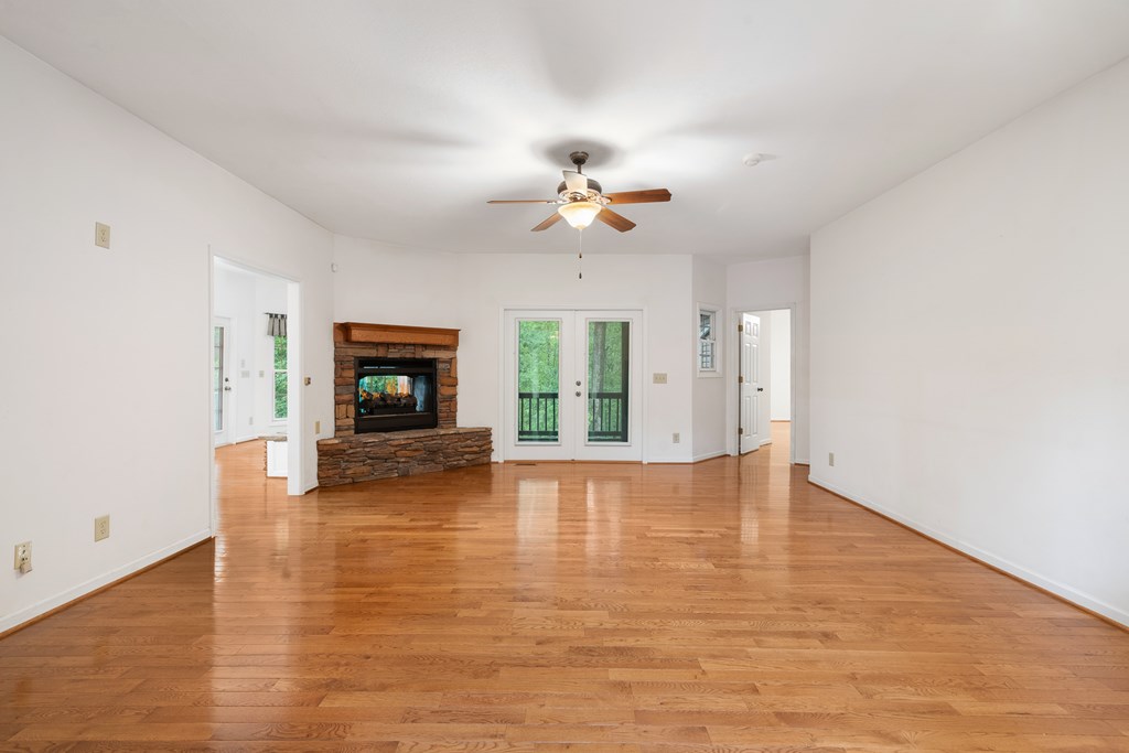 399 Hideaway Hills Road Blairsville, GA 30512 - Photo 35 of 77 an empty room with wooden floor chandelier fan and windows