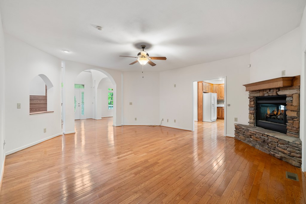 399 Hideaway Hills Road Blairsville, GA 30512 - Photo 37 of 77 an empty room with wooden floor a ceiling fan a fireplace and windows