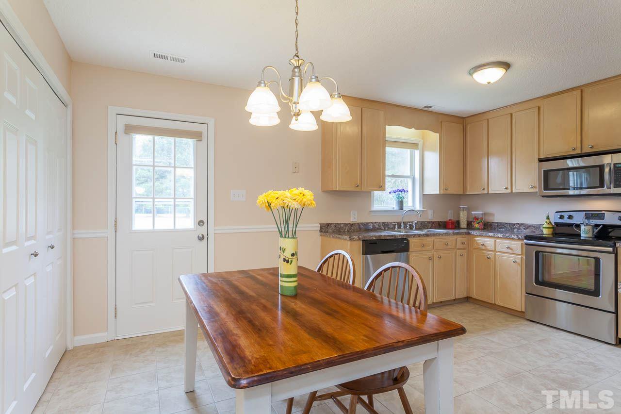 1388 Lee Road Clayton, NC 27520 - Photo 4 of 24 a kitchen with granite countertop a stove a sink a dining table and chairs