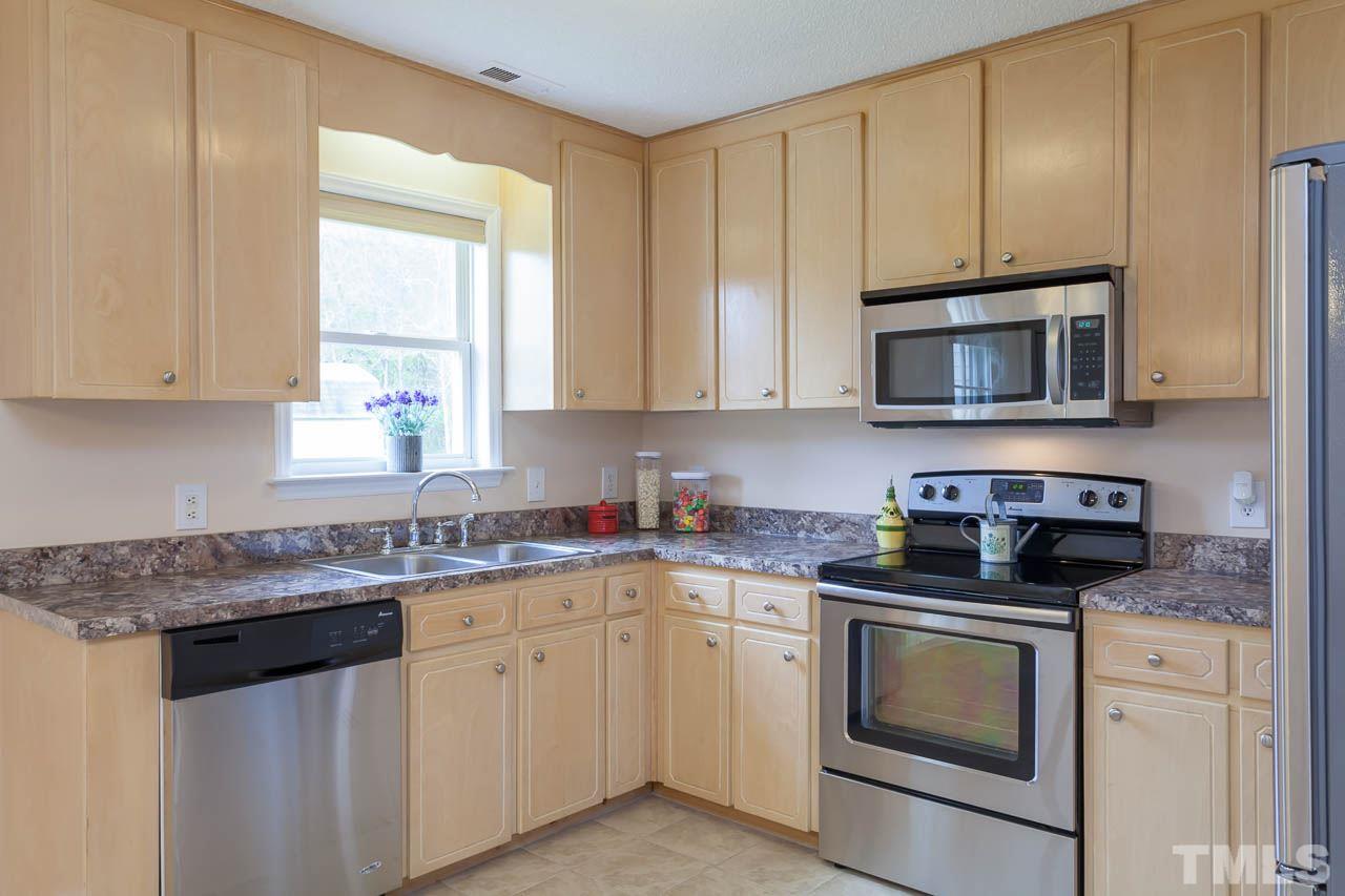 1388 Lee Road Clayton, NC 27520 - Photo 5 of 24 a kitchen with granite countertop white cabinets sink and stainless steel appliances