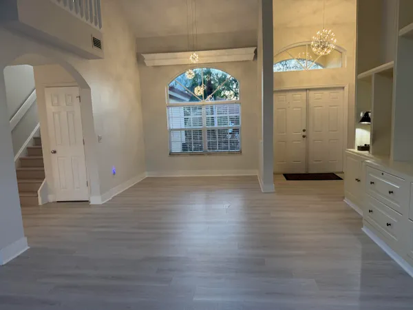 an empty room with wooden floor ceiling fan and window