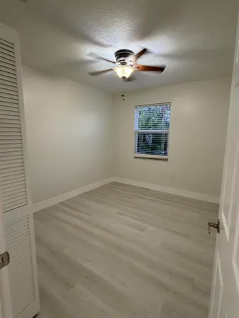 an empty room with a ceiling fan and window