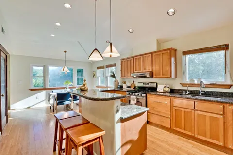 a view of a kitchen counter top space a sink a stove wooden floor and cabinets