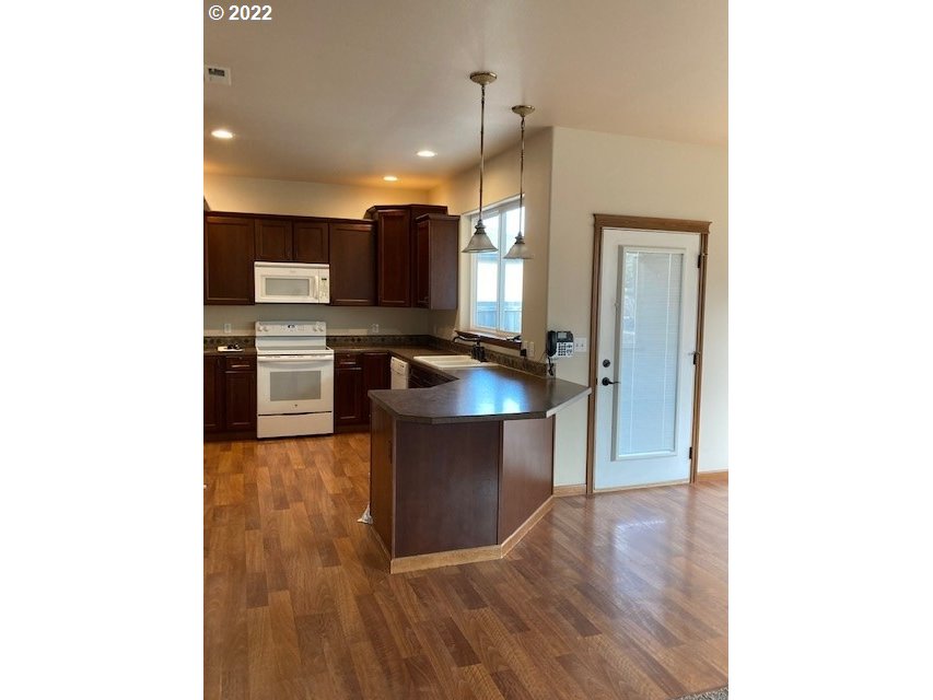 1734 Southwest 3rd Street Pendleton, OR 97801 - Photo 6 of 29 a room with kitchen island stainless steel appliances a stove a sink a refrigerator and wooden floor