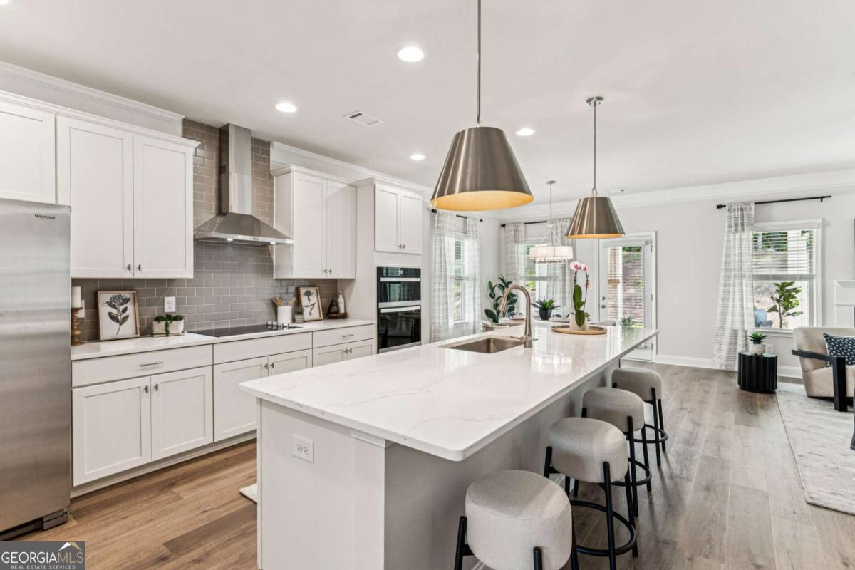 5537 Keswick Drive, Unit 8 Flowery Branch, GA 30542 - Photo 14 of 42 a kitchen with stainless steel appliances a table a sink refrigerator and cabinets