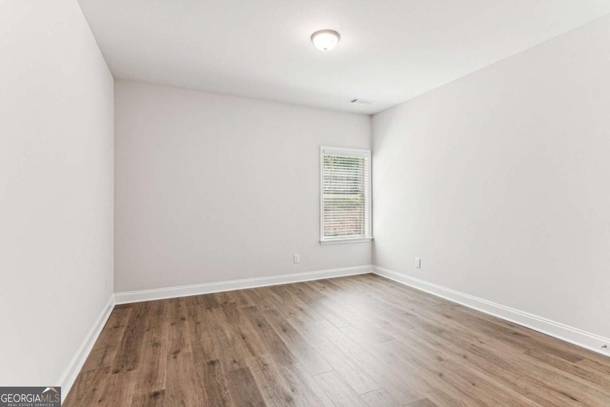 5537 Keswick Drive, Unit 8 Flowery Branch, GA 30542 - Photo 16 of 42 an empty room with wooden floor and windows