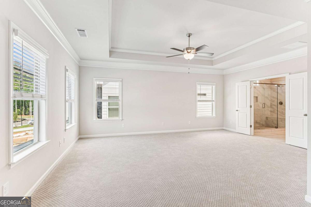 5537 Keswick Drive, Unit 8 Flowery Branch, GA 30542 - Photo 26 of 42 an empty room with chandelier fan and windows