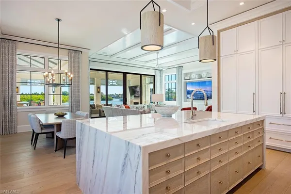 a large kitchen with kitchen island a stove a sink a dining table and chairs with wooden floor