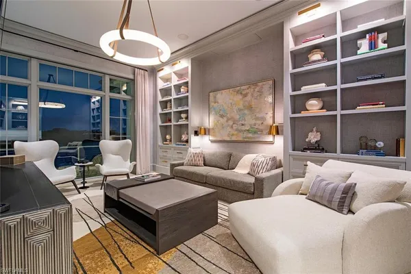 a living room with furniture a chandelier and a bookshelf