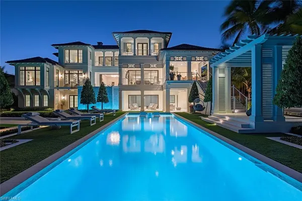 a view of a house with swimming pool lawn chairs and a yard