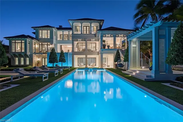 a view of a house with swimming pool lawn chairs and a yard