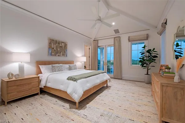 a bedroom with a large bed chandelier and a potted plant