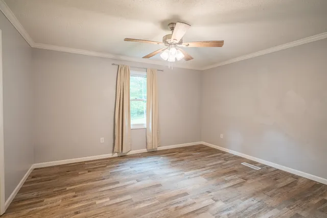 a view of an empty room with wooden floor and a window