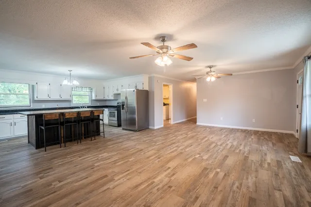 a large kitchen with stainless steel appliances a large counter top a chandelier and a view of kitchen