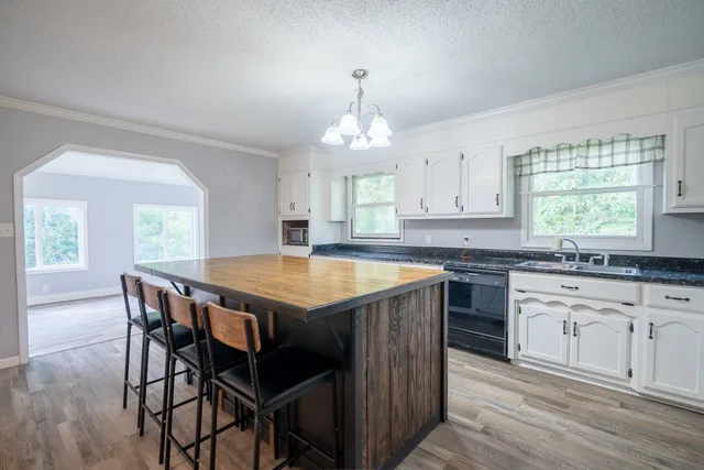 a kitchen with granite countertop a stove a sink dishwasher a dining table and chairs with wooden floor