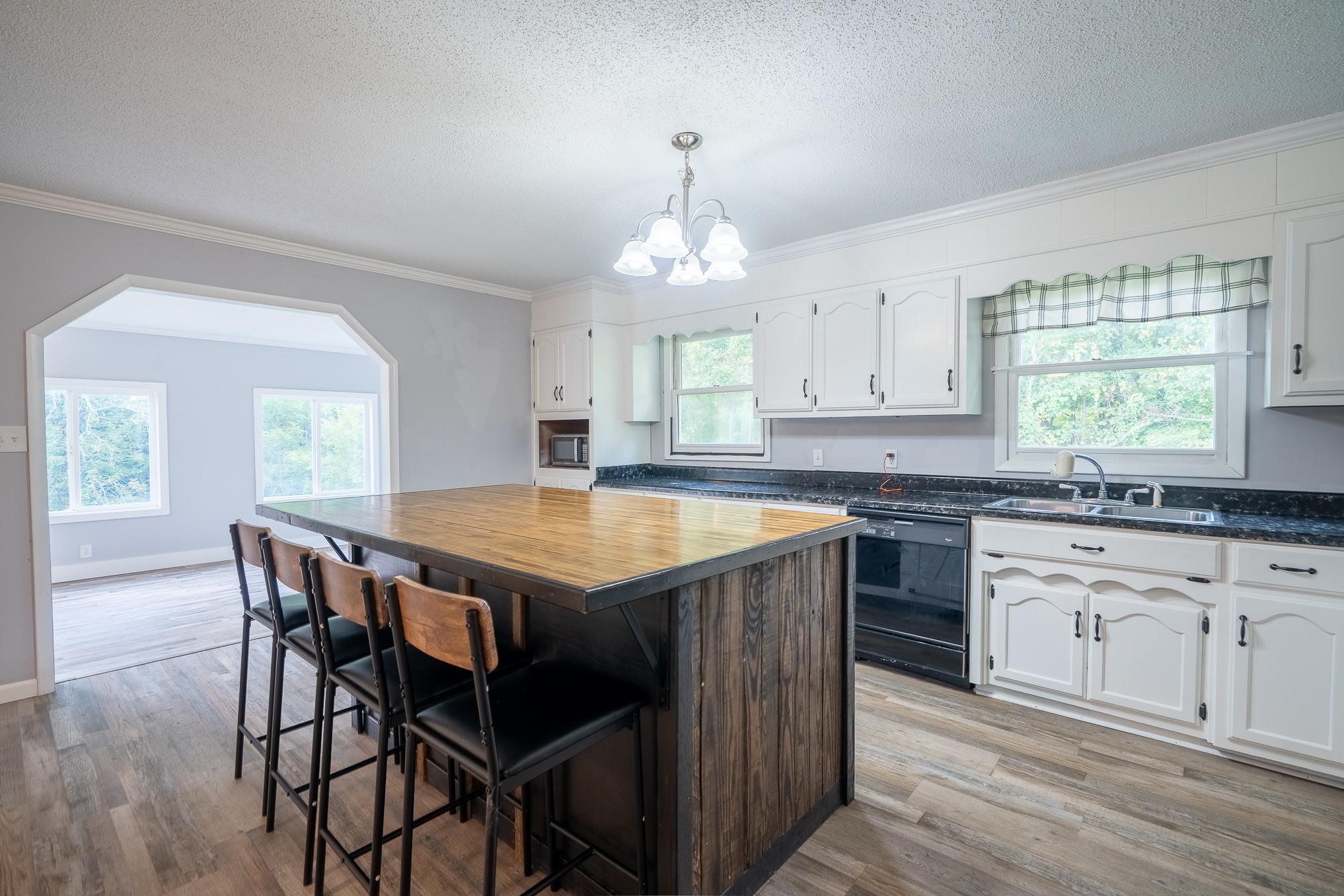 715 Springer Road Hohenwald, TN 38462 - Photo 8 of 30 a kitchen with granite countertop a stove a sink dishwasher a dining table and chairs with wooden floor