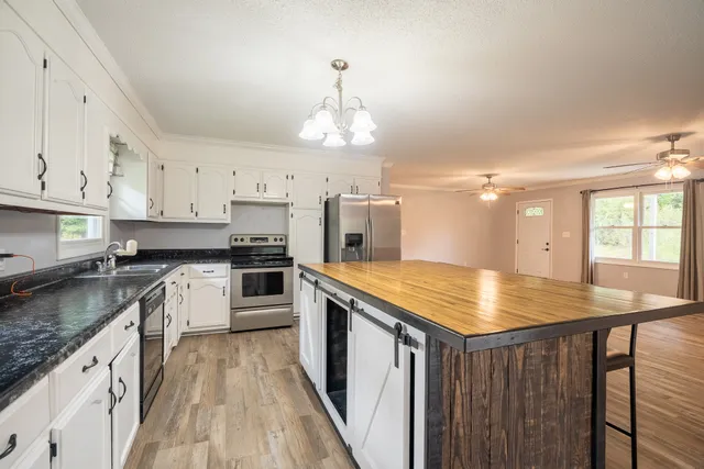 a kitchen with kitchen island granite countertop a stove oven and white cabinets