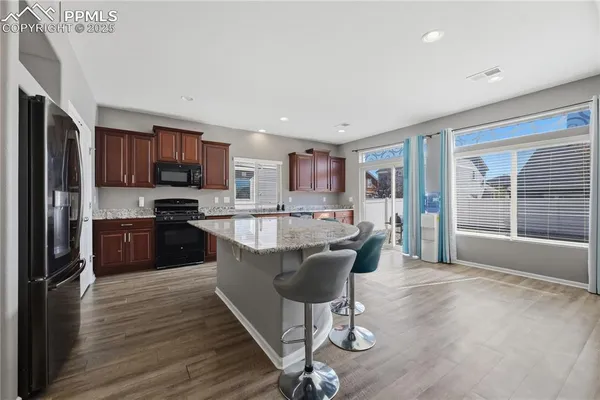 a living room with stainless steel appliances granite countertop a refrigerator a stove a sink dishwasher with a dining table and chairs