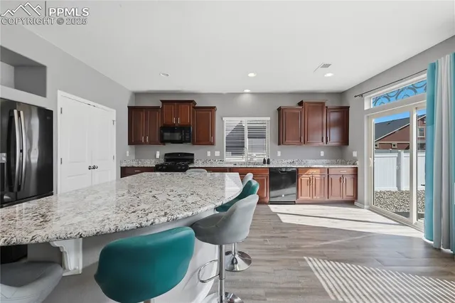 a kitchen with stainless steel appliances granite countertop a stove a sink a microwave a refrigerator and cabinets