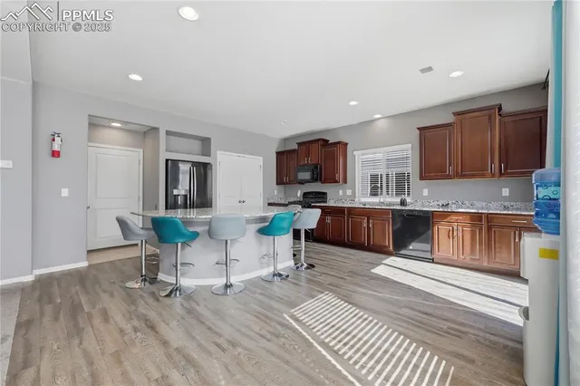 a living room with stainless steel appliances furniture a flat screen tv and kitchen view