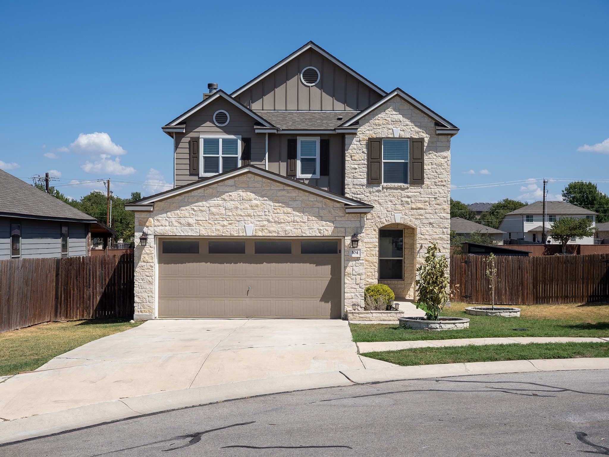 104 Rocroi Drive Georgetown, TX 78626 - Photo 1 of 40 A two-story stone and siding exterior features an attached garage alongside a concrete driveway.