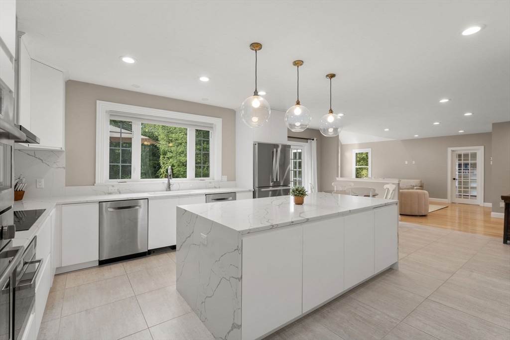 21 Cedar Springs Lane Needham, MA 02492 - Photo 5 of 31 a large white kitchen with a large center island kitchen island a sink a stove and a large window
