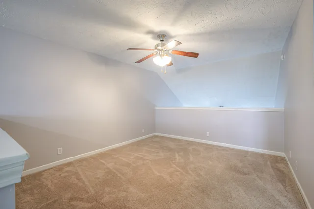 a view of an empty room with a chandelier fan