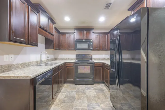 a kitchen with stainless steel appliances granite countertop a refrigerator and a stove top oven