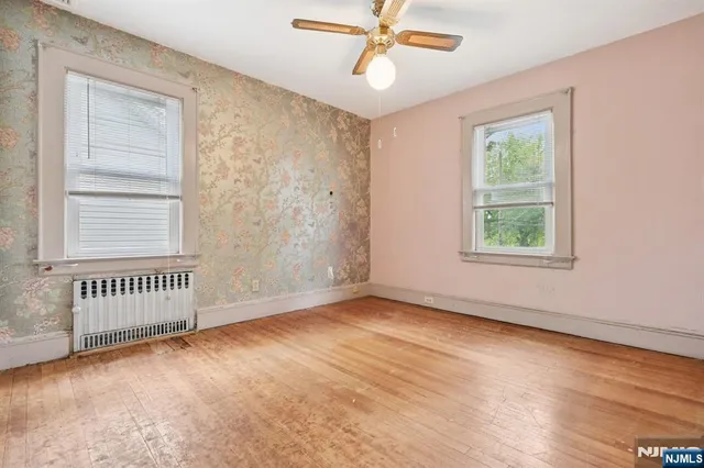 a view of an empty room with a window and wooden floor