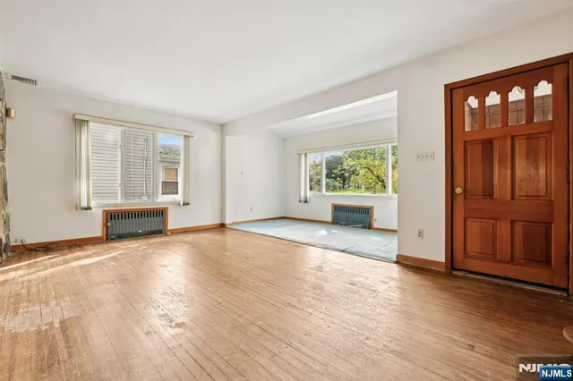a view of an empty room with window and wooden floor