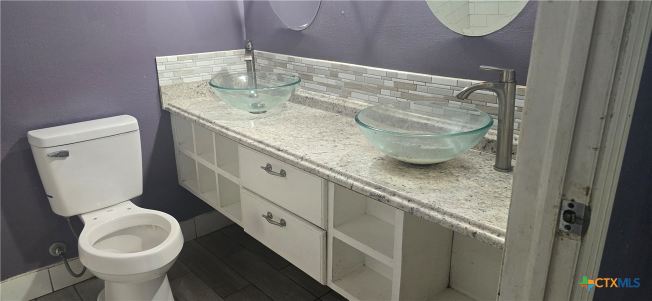 2001 East Forrest Street Victoria, TX 77901 - Photo 11 of 16 a bathroom with a granite countertop sink a toilet and a mirror
