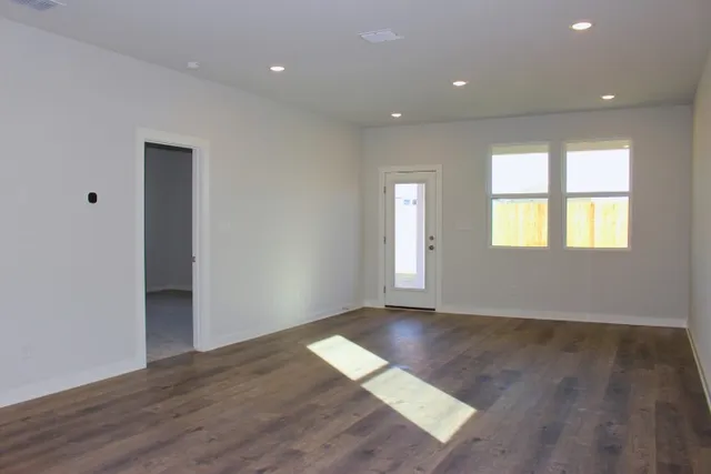 an empty room with wooden floor and windows