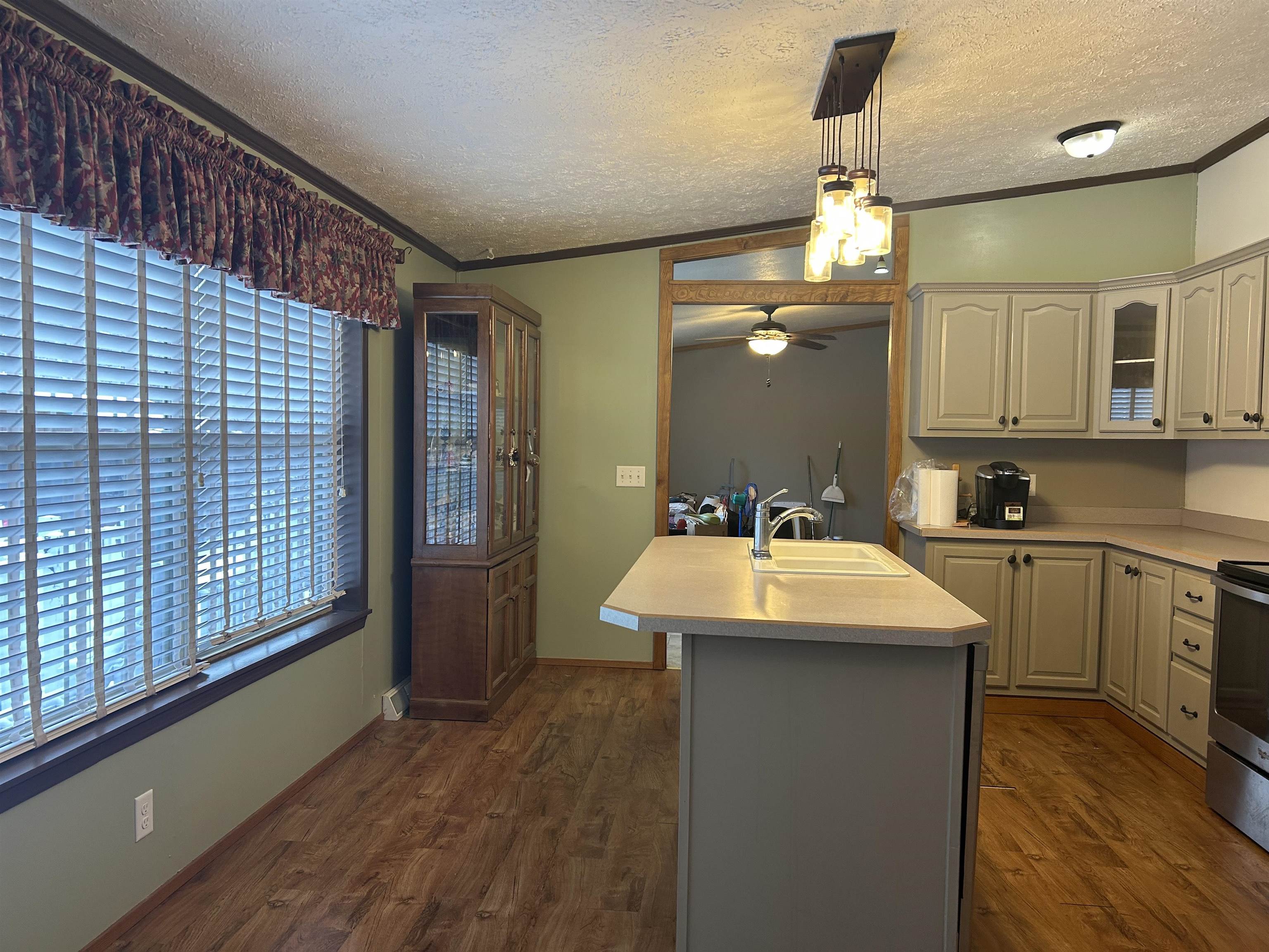 1302 Old North Shore Road Duluth, MN 55804 - Photo 49 of 75 Kitchen featuring an island with sink, light countertops, crown molding, a textured ceiling, and stainless steel range with electric cooktop