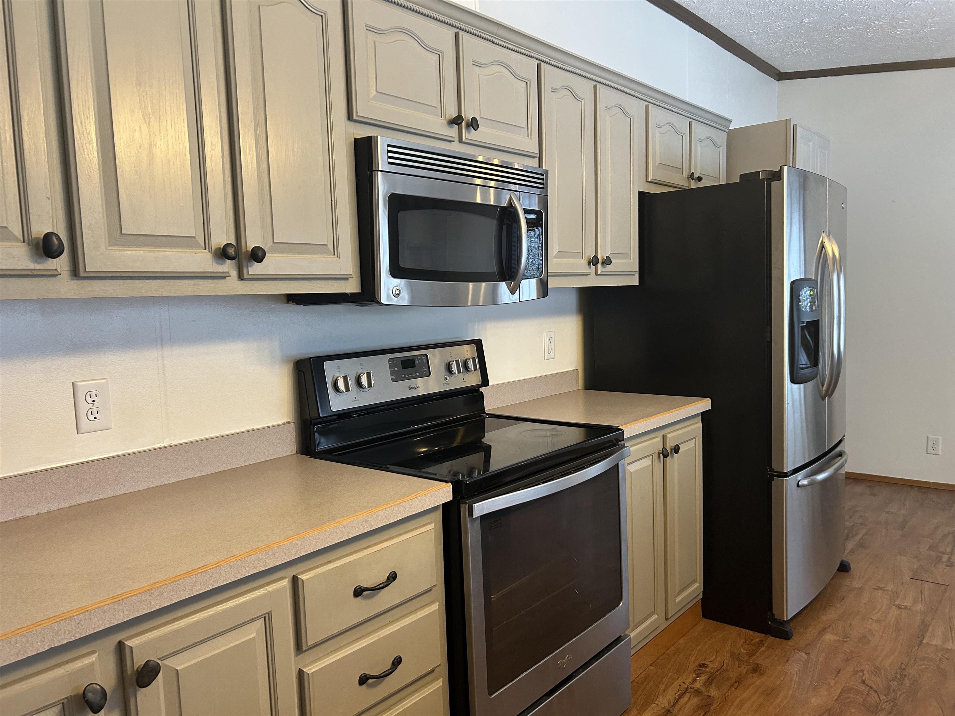 1302 Old North Shore Road Duluth, MN 55804 - Photo 50 of 75 Kitchen featuring stainless steel appliances, crown molding, light countertops, dark wood-type flooring, and a textured ceiling