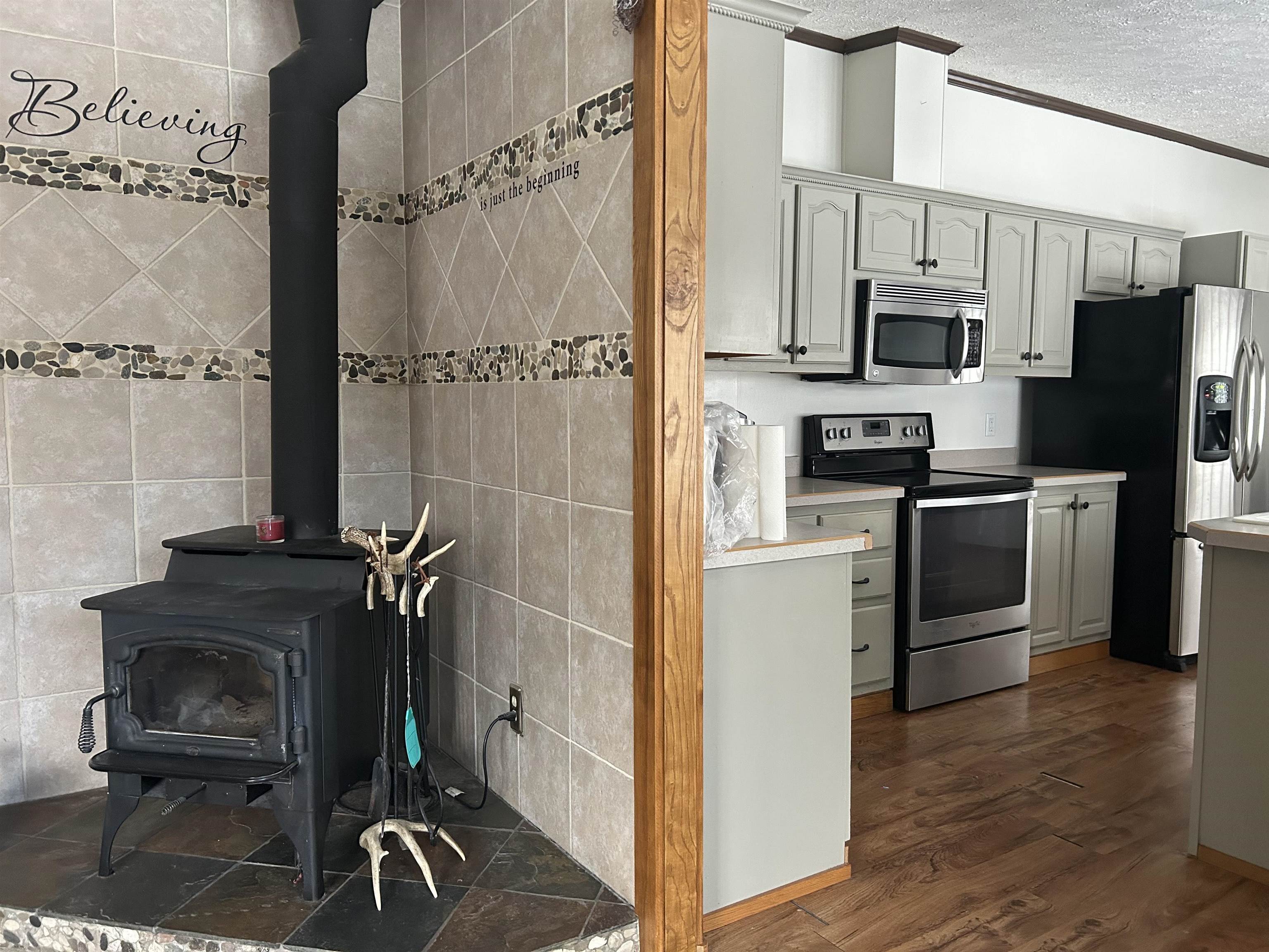 1302 Old North Shore Road Duluth, MN 55804 - Photo 66 of 75 Kitchen with stainless steel appliances, a wood stove, light countertops, dark wood-type flooring, and a textured ceiling