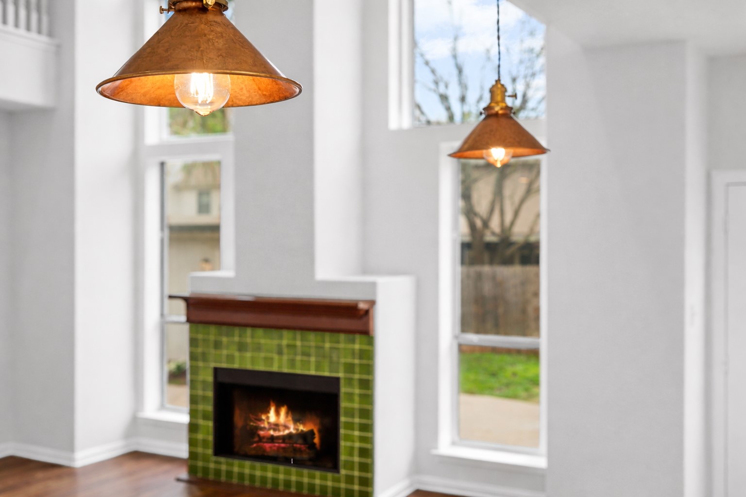 813 Caribou Ridge Trail Pflugerville, TX 78660 - Photo 17 of 39 Designer copper pendant lighting highlights the open living space with tall windows, abundant natural light, and a striking tiled fireplace.