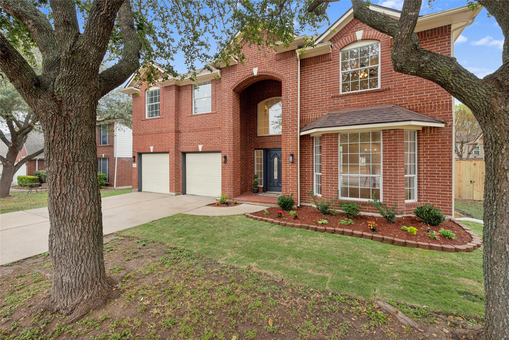 813 Caribou Ridge Trail Pflugerville, TX 78660 - Photo 2 of 39 Grand brick façade, mature trees, and welcoming curb appeal set the stage for this beautifully renovated six-bedroom luxury home in Pflugerville’s Club at Wells Point community.