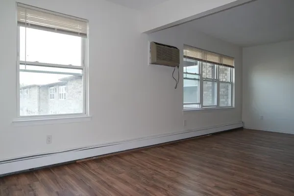 a view of an empty room with wooden floor and a window