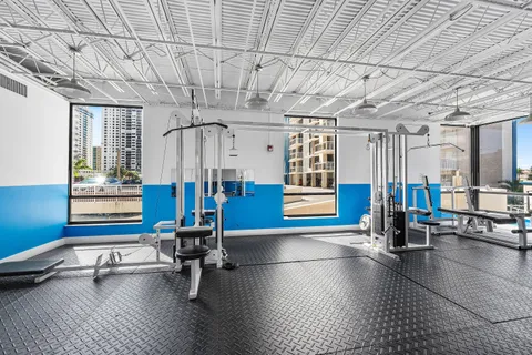 a gym room with lots of furniture and windows