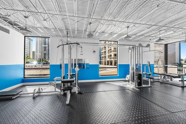 a gym room with lots of furniture and windows