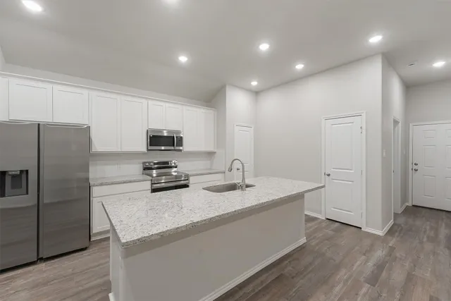 a kitchen with a sink a microwave a refrigerator and cabinets