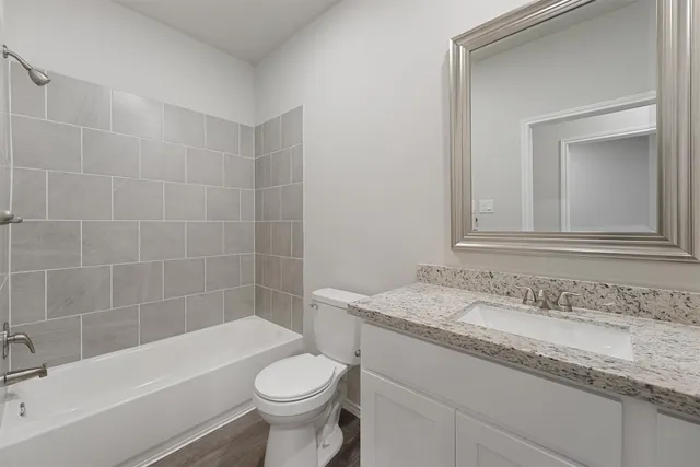 a bathroom with a granite countertop sink a toilet and bathtub