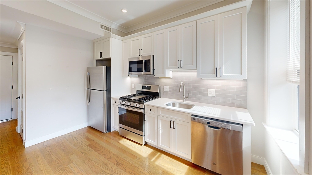 191 Porter Street, Unit 4 Boston, MA 02128 - Photo 2 of 8 a kitchen with stainless steel appliances granite countertop a stove a refrigerator and a microwave