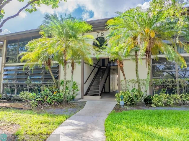 a view of a house with a palm tree in a yard with potted plants