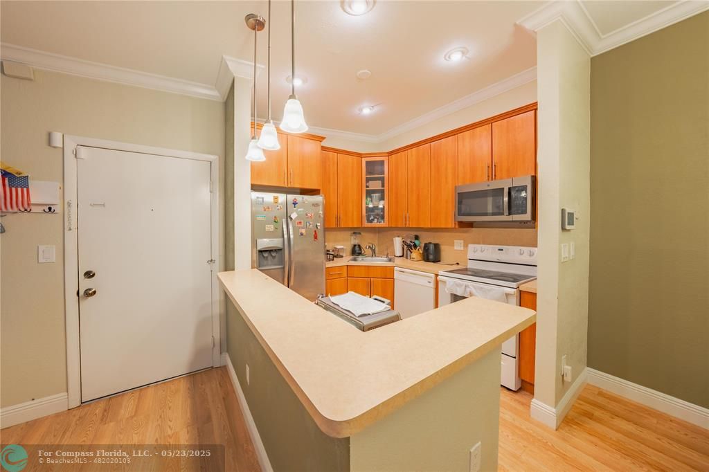 9614 West McNab Road, Unit 204 Tamarac, FL 33321 - Photo 5 of 37 a kitchen with stainless steel appliances a refrigerator a sink dishwasher and wooden cabinets with wooden floor