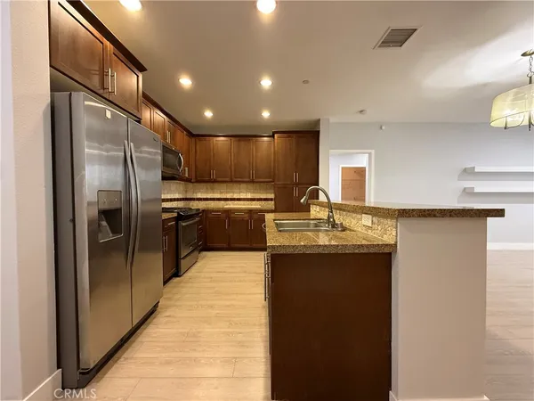 a kitchen with stainless steel appliances granite countertop a sink refrigerator and cabinets