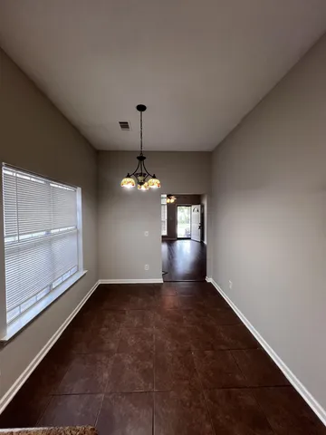 an empty room with chandelier fan and windows