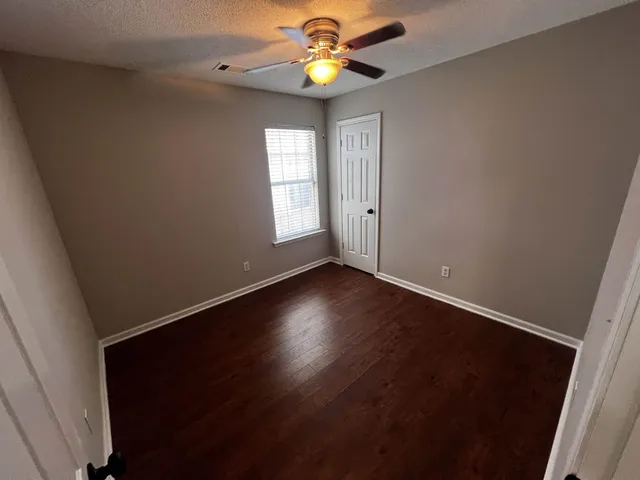 a view of an empty room with window and wooden floor