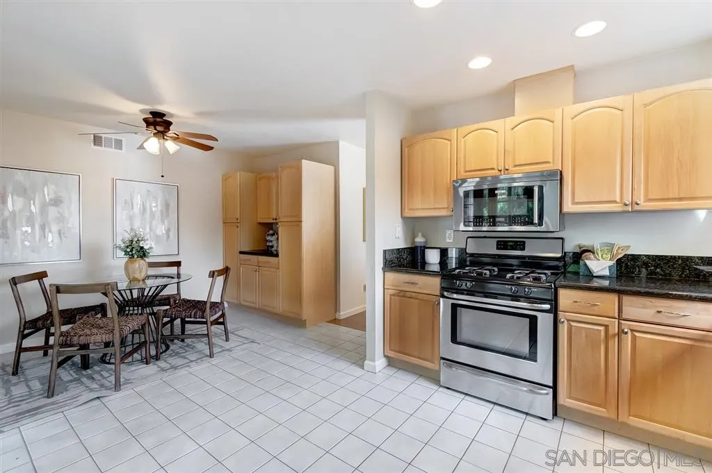 13856 Olive Grove Place Poway, CA 92064 - Photo 11 of 25 a kitchen with stainless steel appliances granite countertop a stove a sink a dining table and chairs