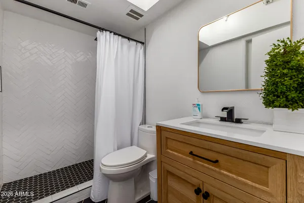 a bathroom with a granite countertop sink toilet and mirror